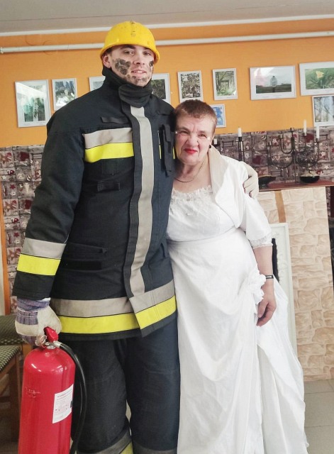 2 jelmezes lakó mennyasszonynak és tűzoltónak beöltözve mosolyog a kamerába